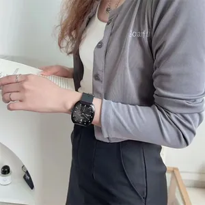 Detail of square black quartz watch with silicone strap on model in a casual setting