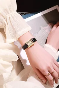 Close-up of elegant gold square quartz watch with black leather strap and Roman numerals