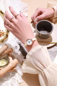 Detail of rose gold quartz watch with white leather strap on female wrist