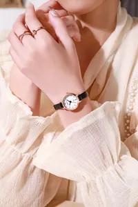 Close-up of elegant women's quartz watch with black leather strap and golden rings