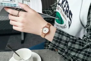 Montre à quartz or rose avec cadran blanc portée au poignet dans une scène de vie