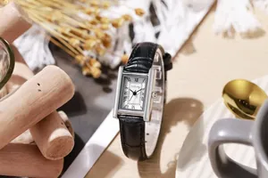 Detail of a rectangular silver watch with black crocodile leather strap and roman numerals