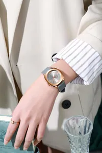 Detail van roségouden quartzhorloge met grijze siliconen band om een vrouwelijke pols