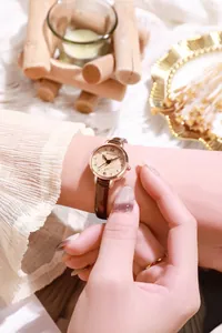 Macro detail of elegant quartz watch with rose gold case and brown leather strap