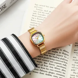 Golden square watch with pink-teal gradient dial worn by model over book background
