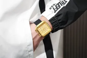 Close-up of Belushi square gold chronograph watch with black silicone strap on wrist