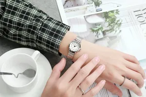 Gros plan d'une montre en acier argenté avec cadran blanc au poignet d'une femme élégante