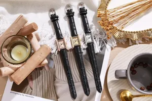 Three vintage rectangular ladies watches with leather straps on a white knit blanket
