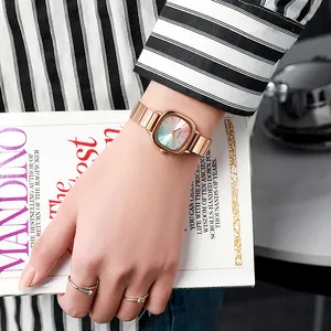 Detail of rose gold quartz watch with gradient dial and matching minimalist rings