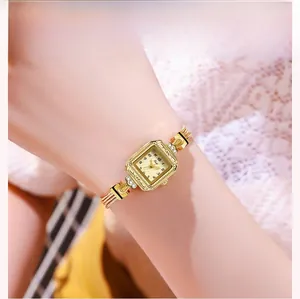 Gros plan d'une montre de luxe à cadran carré doré avec bracelet en chaîne de métal