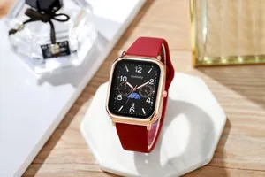 Detail van een rechthoekig roségouden horloge met rode siliconen band en zwarte wijzerplaat