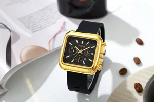 Detail of square gold quartz watch featuring a black dial and silicone strap on coffee beans
