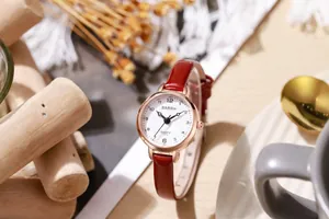 Detail of rose gold quartz watch featuring a red leather strap and vintage Arabic numerals