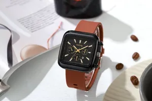 Detail view of square black watch case with red-brown silicone strap and gold accents