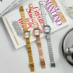 Detailed view of three minimalist metal watches with gradient dials on a book