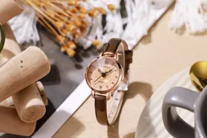 Close-up of rose gold watch dial with brown leather strap and sunray champagne finish