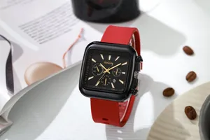 Detail of square black metal watch case with red silicone strap and textured dial