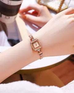 Détail d'une montre carrée vintage en or rose avec strass latéraux et bracelet tissé