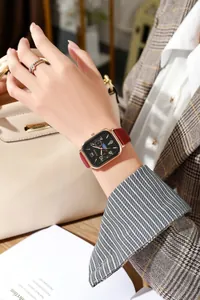 Detail van roségouden rechthoekig horloge met rode lederen band en multifunctionele wijzerplaat