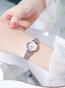 Detail of silver mesh strap and white dial with crystal markers on woman's quartz watch