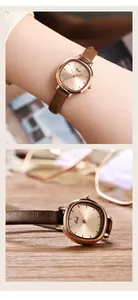 Detailopname van Gedi roségouden horloge met slanke bruine lederen band op houten basis