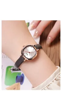 Close-up of elegant rose gold rectangular watch with grey leather strap on wrist