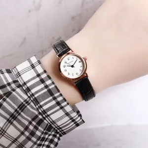Detailed close-up of a women quartz watch with white dial, date window, and black leather strap