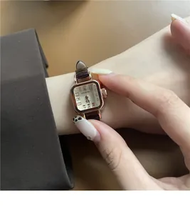 Dettaglio dell'orologio vintage quadrato in oro rosa con cinturino in pelle sul polso