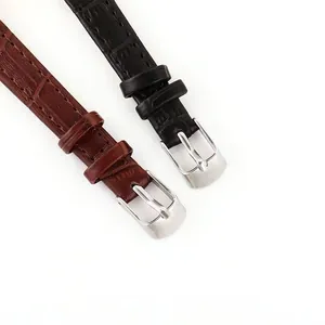 Detail of black and brown crocodile textured leather watch straps with silver buckles