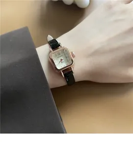 Dettaglio dell'orologio quadrato oro rosa con cinturino in pelle nera al polso