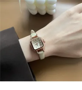 Dettaglio di un orologio vintage quadrato con cinturino in pelle verde al polso di donna