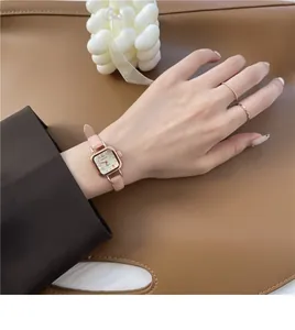 Orologio quadrato in oro rosa con cinturino in pelle rosa indossato sul polso in stile lifestyle