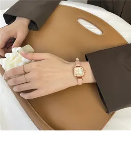 Dettaglio di un orologio quadrato in oro rosa con cinturino in pelle rosa indossato da una donna