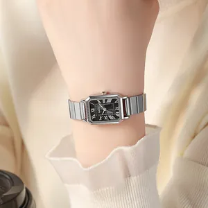Close-up of a square silver quartz watch with a black Roman numeral dial on a female wrist