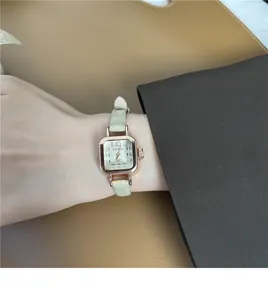 Dettaglio di un orologio quadrato vintage in oro rosa con cinturino in pelle beige al polso