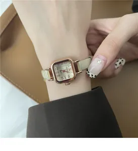 Primo piano di un orologio vintage quadrato in oro rosa con cinturino sottile in pelle verde