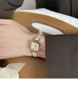 Dettaglio macro dell'orologio quadrato vintage con cassa oro rosa e cinturino beige