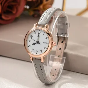 Detail view of a rose gold quartz watch with a white dial and textured grey leather strap