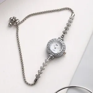 Détails d'une montre gourmette argentée avec lunette en strass et fermoir à coulisse