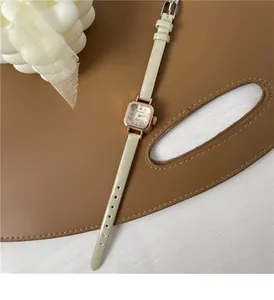 Dettaglio dell'orologio al quarzo quadrato con cinturino in pelle beige e vassoio