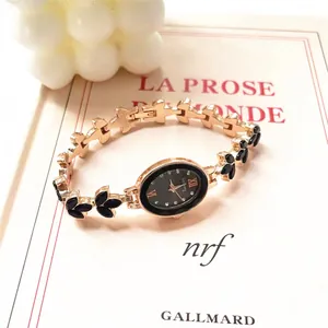 Detail of elegant gold oval watch with black dial placed on a vintage French book
