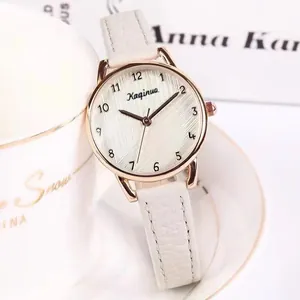 Detail of rose gold ladies quartz watch with white leather strap on a white coffee cup