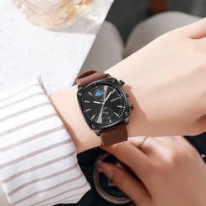 Men's square black watch with brown silicone strap worn on wrist in a casual setting