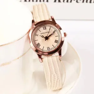 Montre femme élégante or rose avec bracelet crème motif lézard sur une tasse