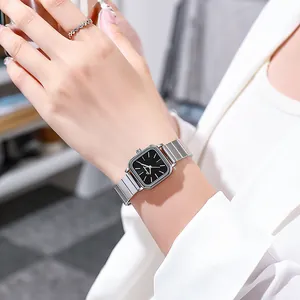 Detail of square silver watch with black dial on wrist paired with textured ring