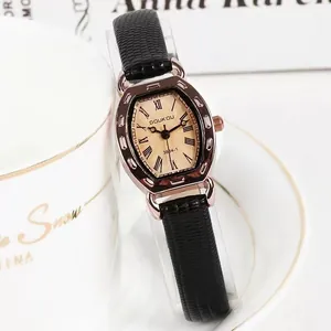 Detail van roségouden tonneau horloge met zwarte leren band naast een koffiekopje