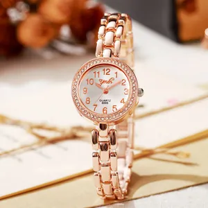 Détail macro d'une montre à quartz or rose avec lunette en strass et chiffres arabes