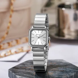 Detail of square silver steel watch on marble base with minimalist bar scale dial