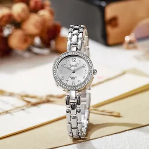 Détail d'une montre à quartz argentée pour femme avec lunette en strass sur fond vintage