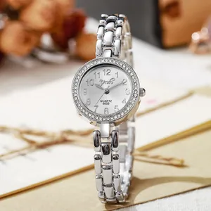 Montre femme élégante en argent avec lunette en strass et bracelet chaîne sous lumière douce